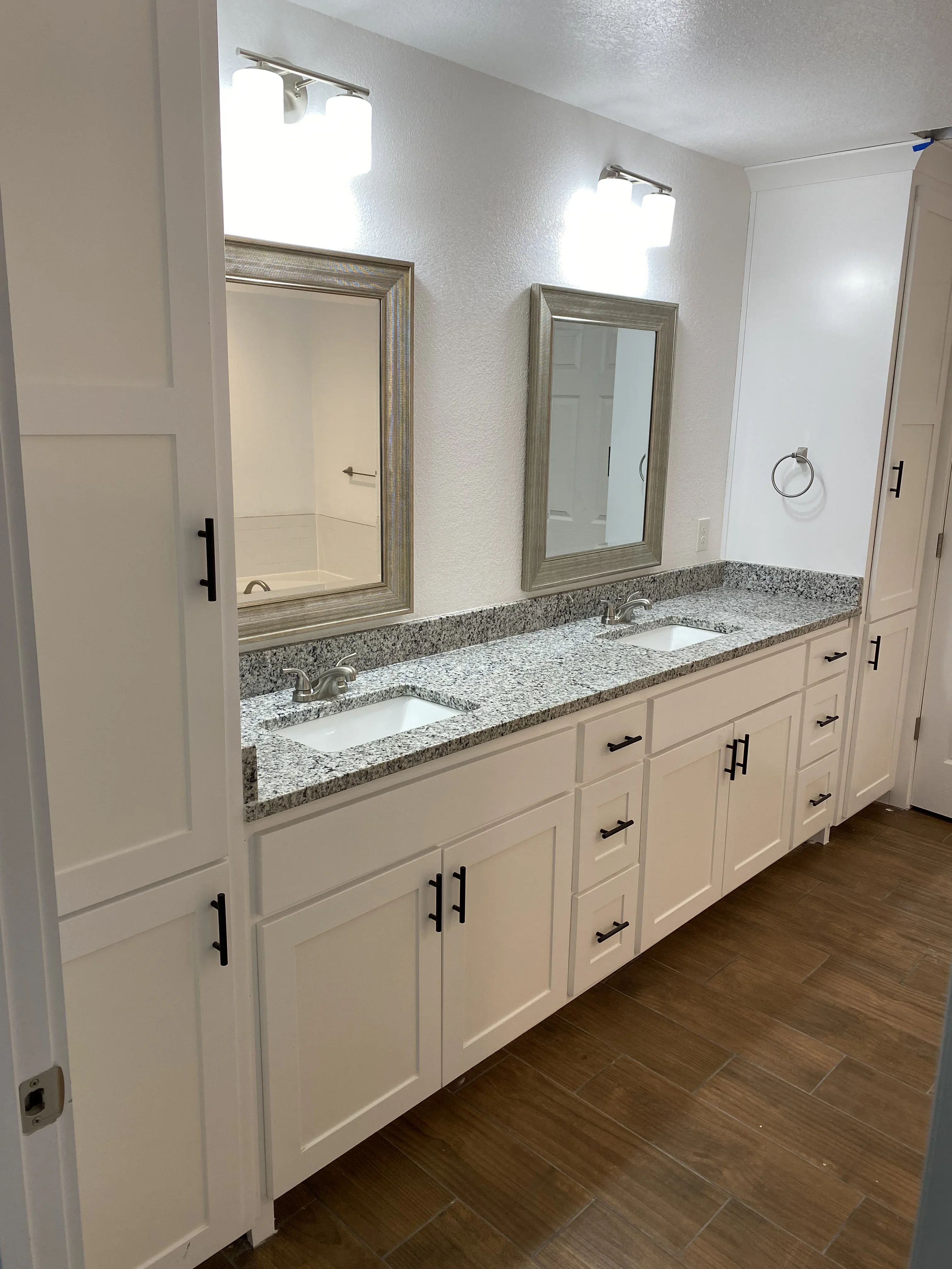 Dual-sink bathroom vanity with granite countertop, white cabinetry, and framed mirrors