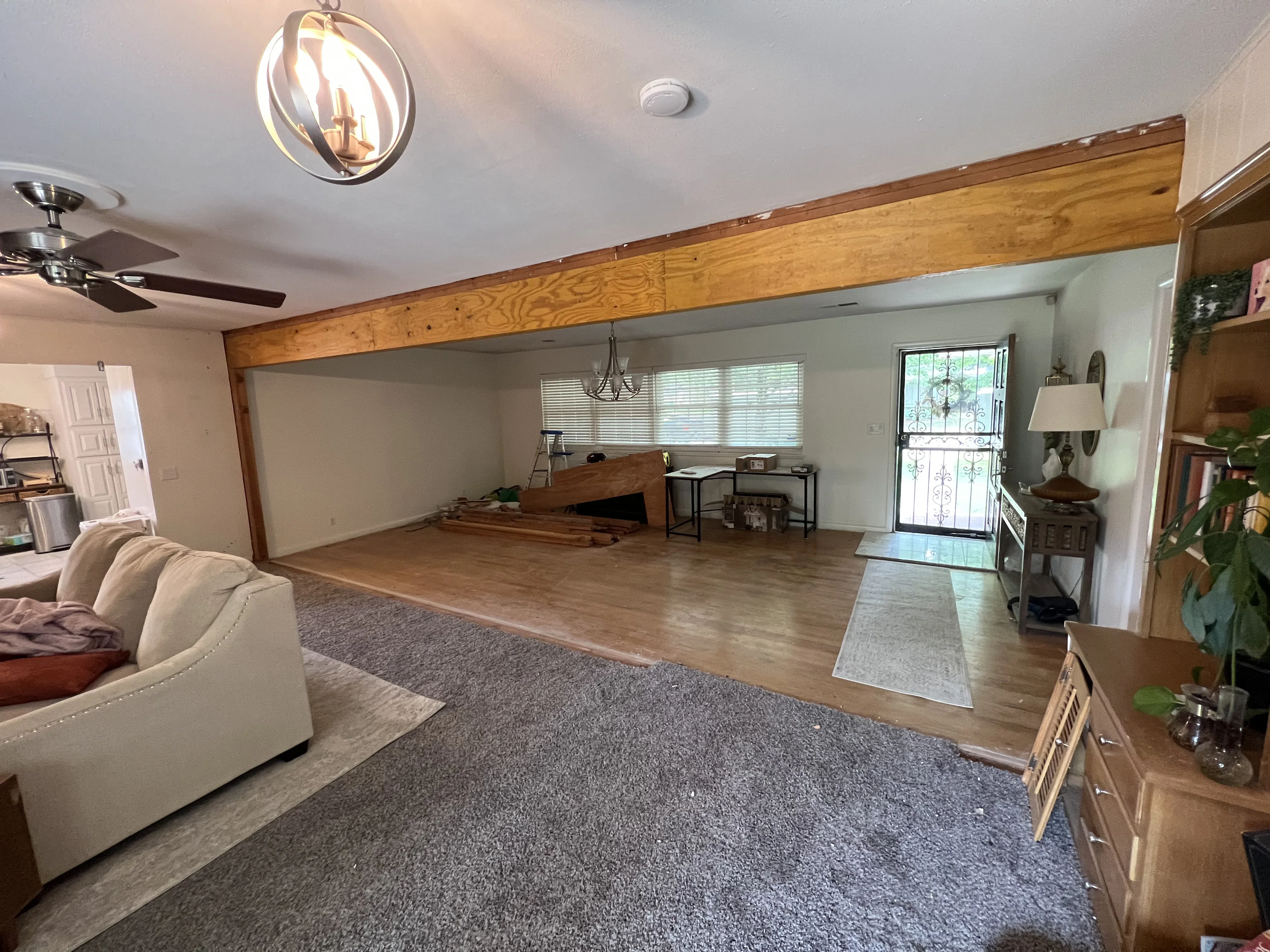 Open concept living room with exposed wooden beam, hardwood flooring, and recessed lighting