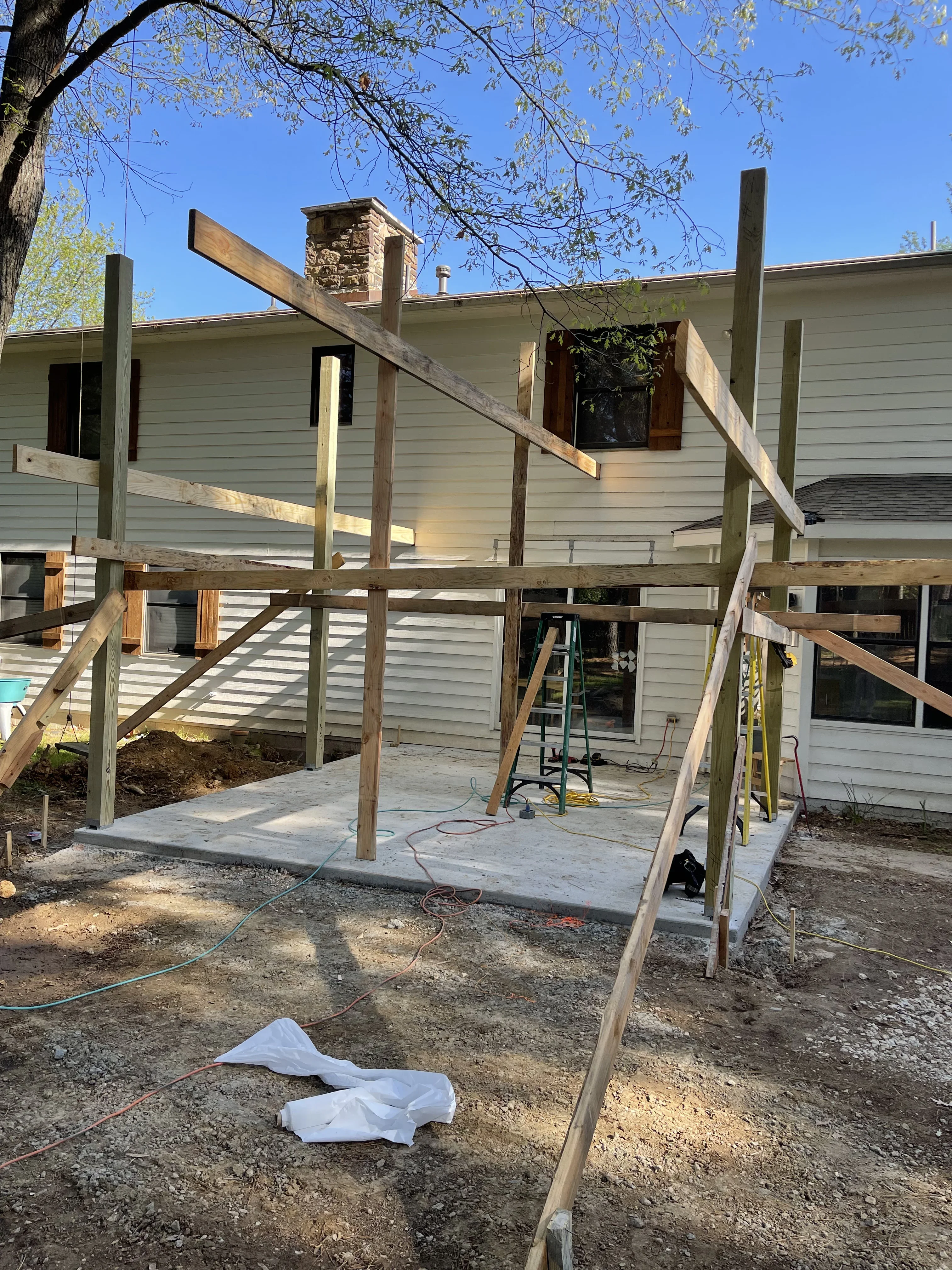 Pressure-treated wood deck framing with posts and beams over concrete patio foundation