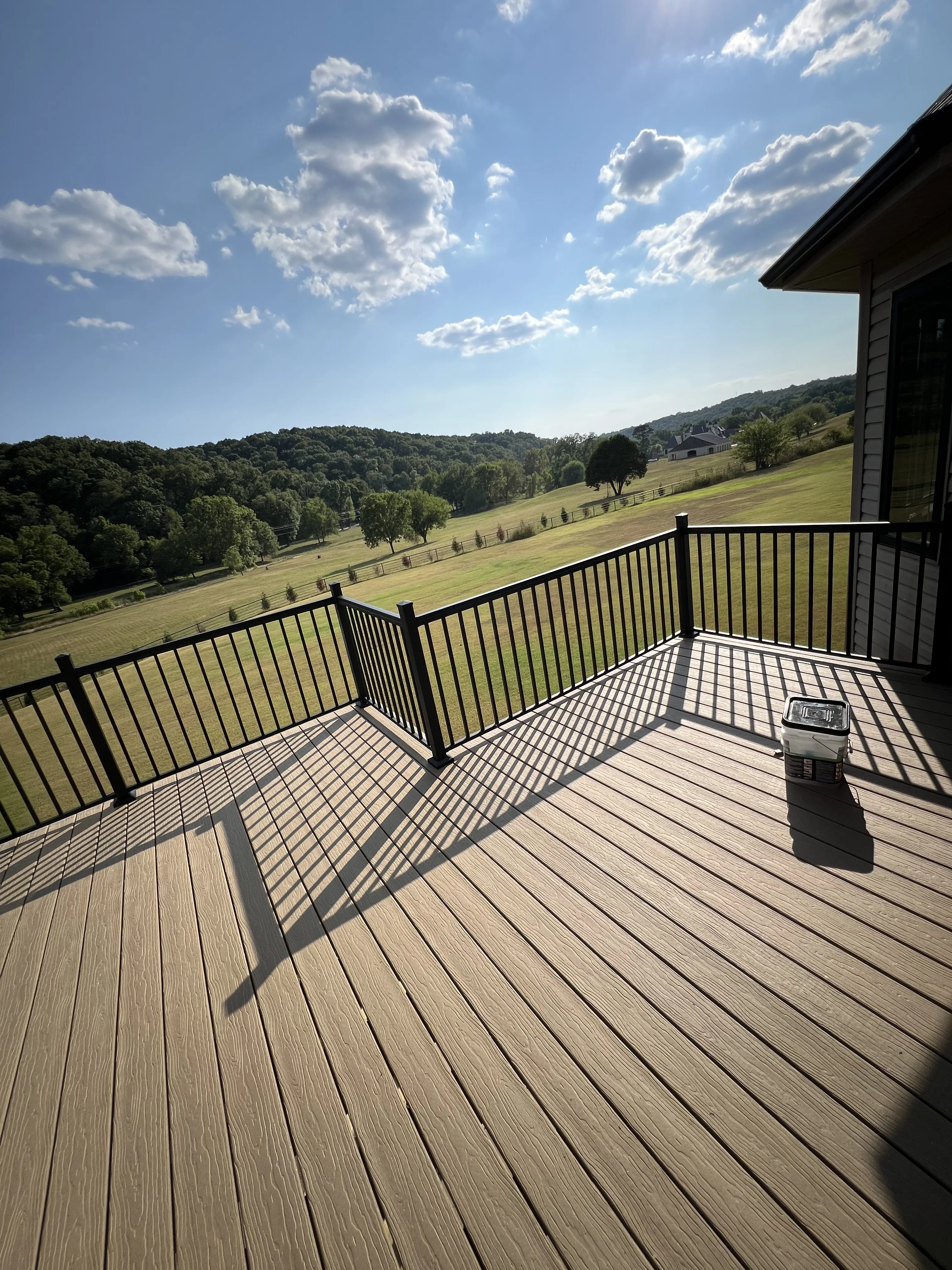 Composite deck with black metal railing overlooking valley landscape