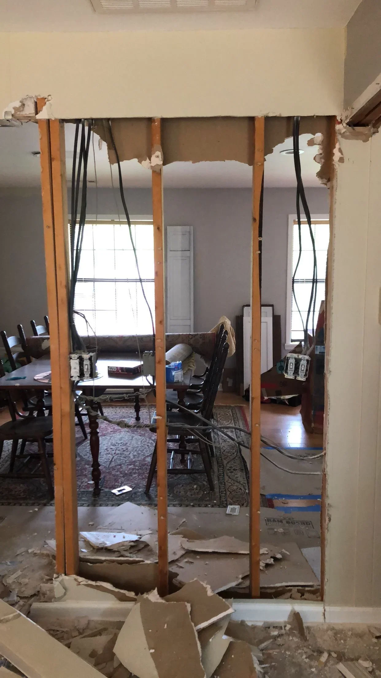 Interior wall removal with wooden beam framing, electrical conduit, and drywall demolition