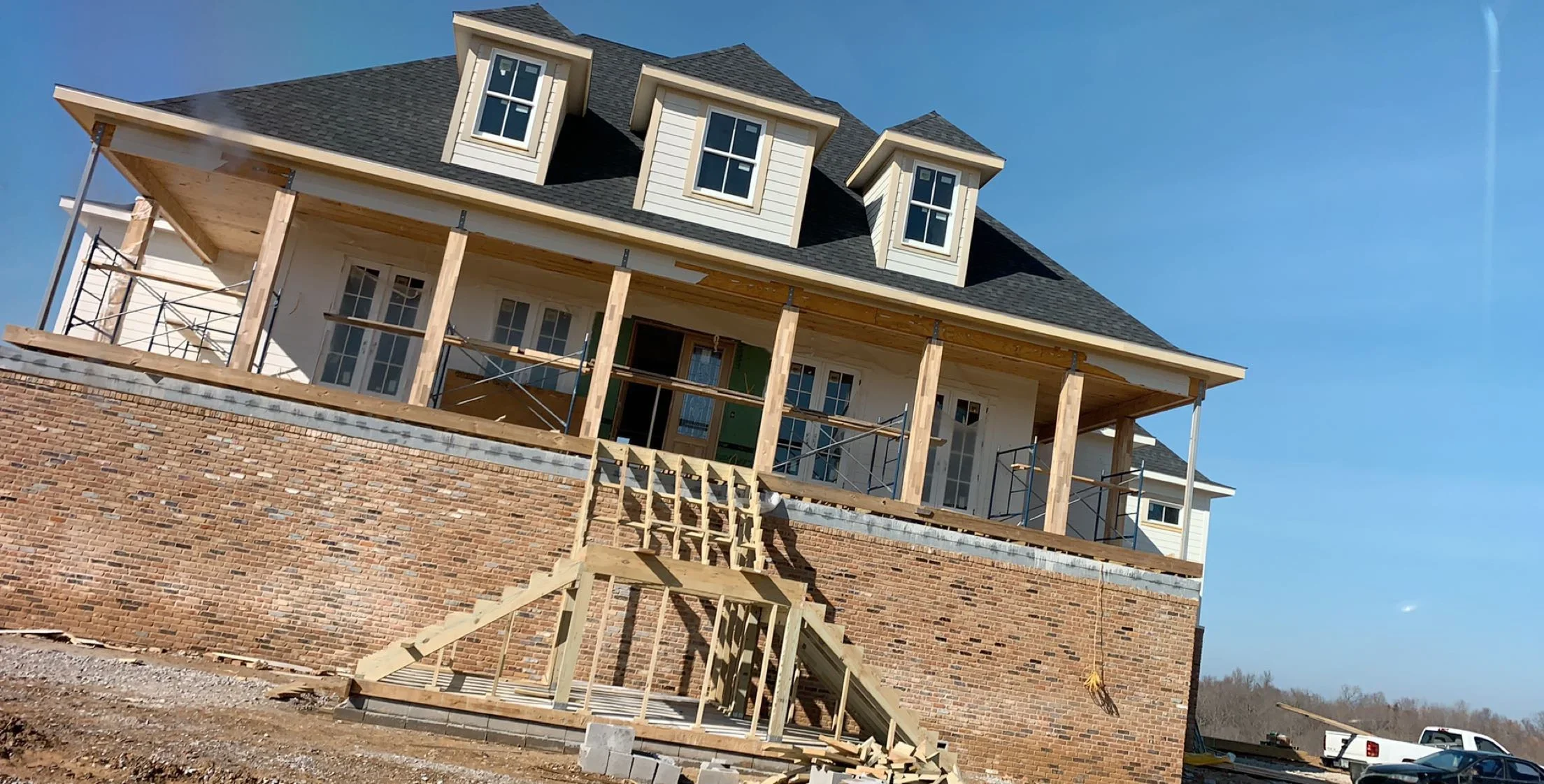 Two-story home with brick foundation, wood framing, dormers, and timber deck construction
