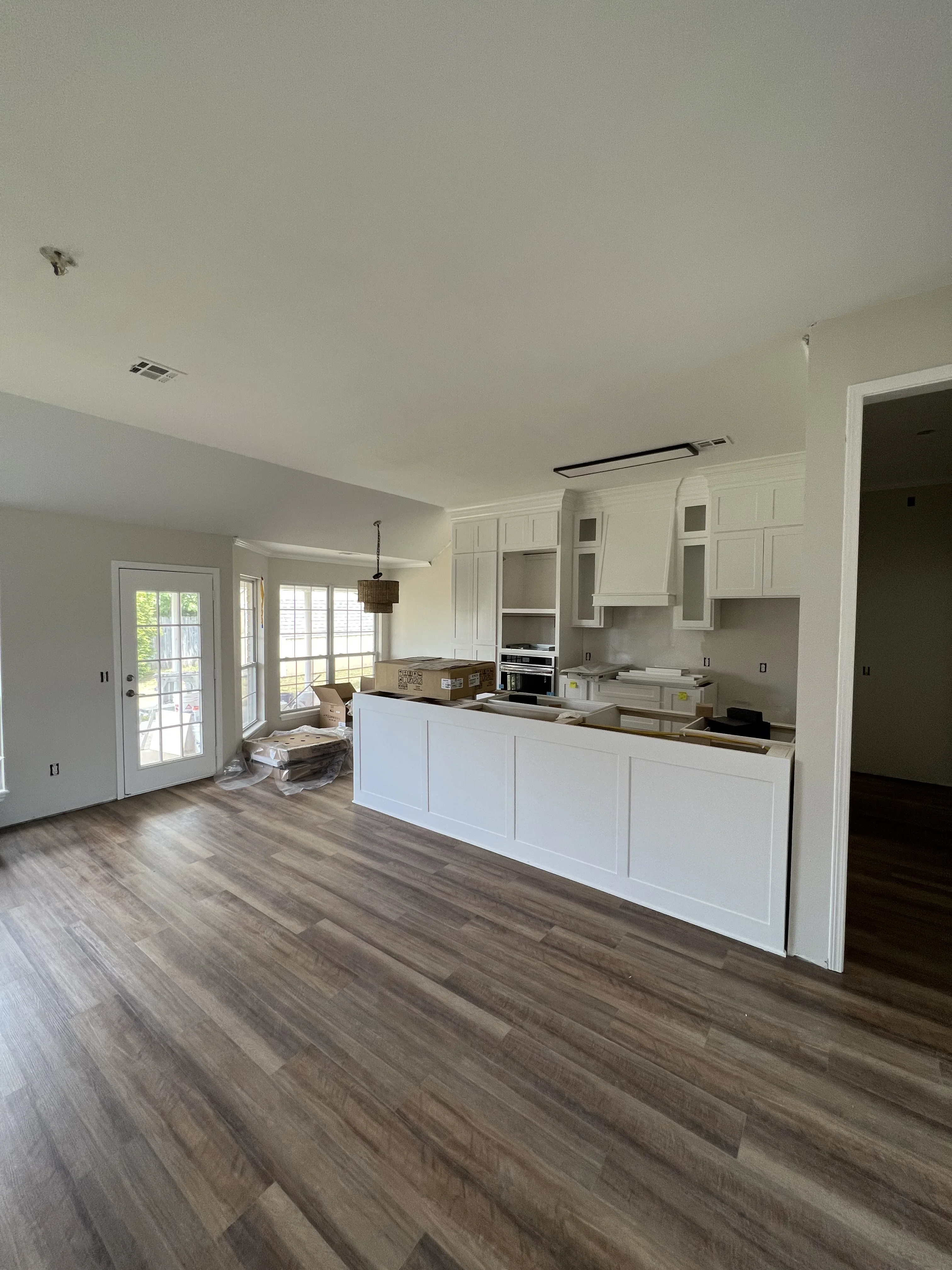 White shaker cabinets, stainless steel appliances, island, vinyl plank flooring, open kitchen layout