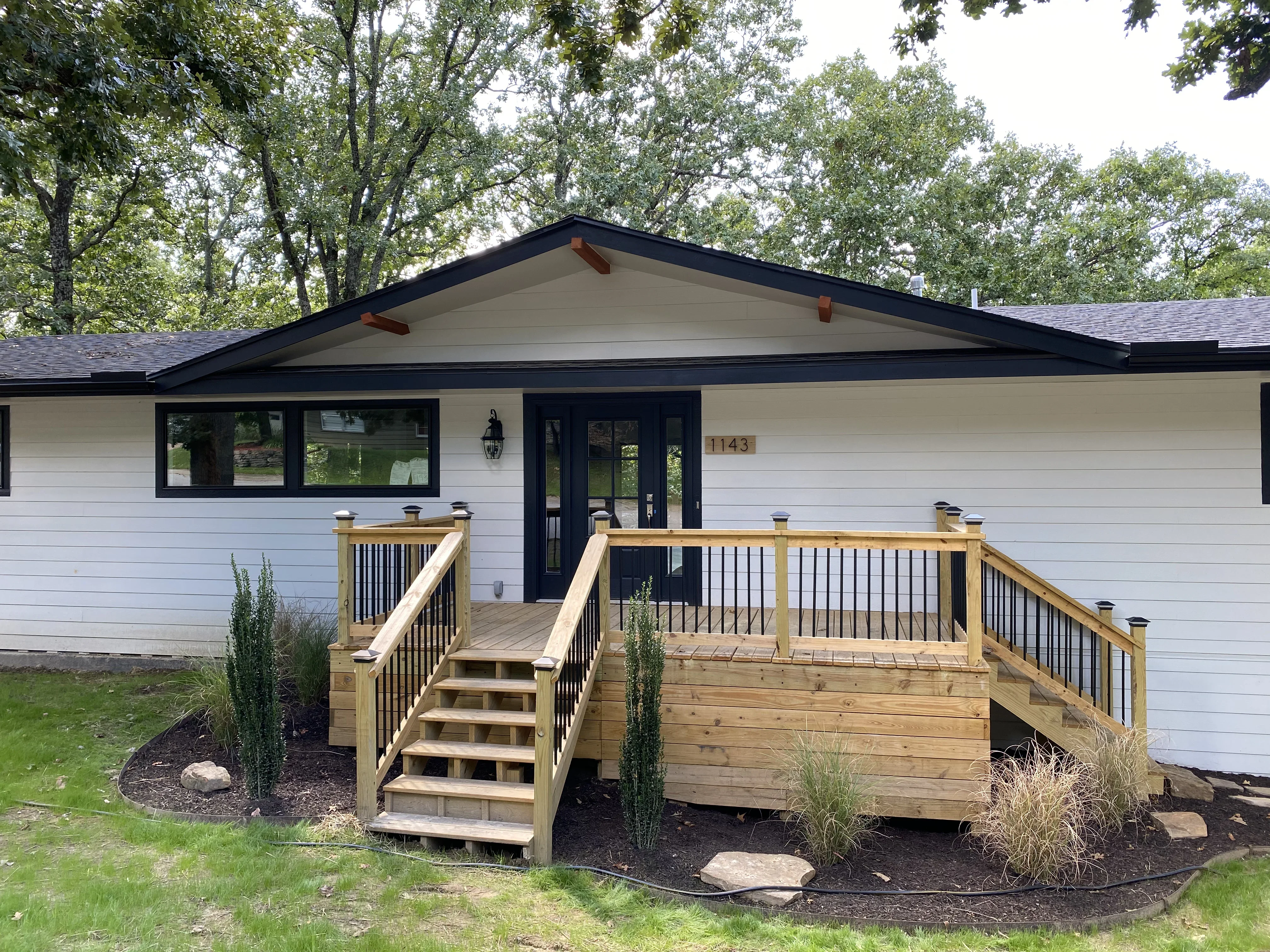 White ranch home with black trim, new composite deck, black metal railings, and updated windows