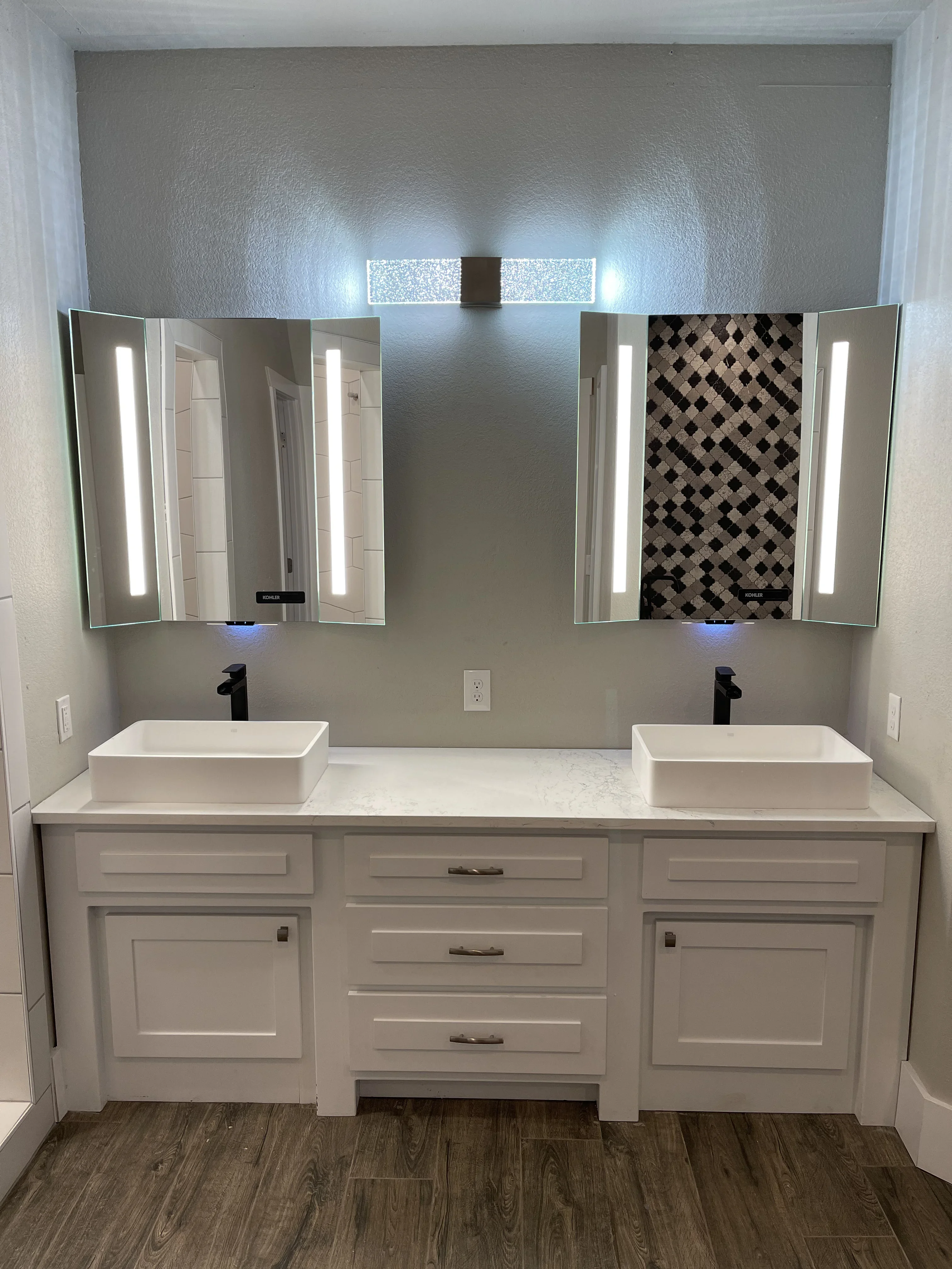 Dual-sink vanity with white cabinetry, quartz countertop, LED mirror cabinets, and black faucets